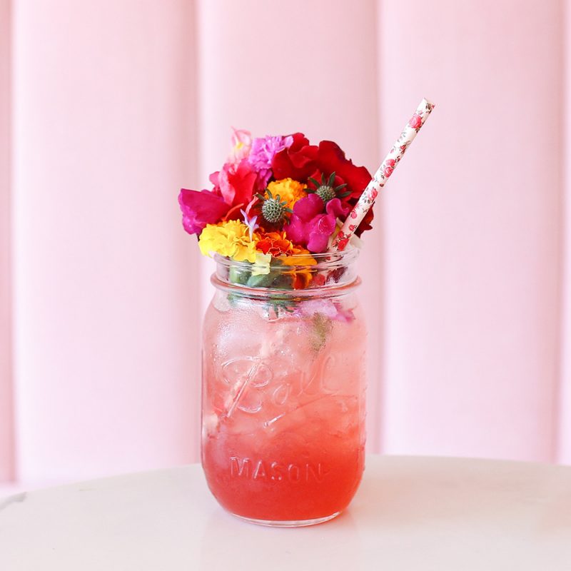 Captivating image of the Pink Mojito, showcasing a visually stunning and fresh-looking pink gradient drink adorned with colorful flowers. Crafted with 1 1/2 oz 3 Lacs Pink grapefruit rum, 8 fresh mint leaves, 1 oz Del Monte Guava juice, and 1/2 oz lime juice, this delightful concoction is topped with lemon-lime-flavored soft drink. A visually appealing and flavorful cocktail promising a perfect balance of sweetness and freshness.
